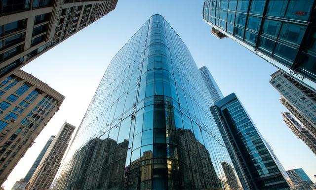 Modern glass office building reflecting the city sky, representing modern commerce